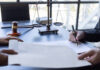a imagem mostra o símbolo da justiça na mesa e um homem assinando um documento
