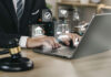 Mão do empresário ou advogado com ícone de serviços jurídicos na tela do laptop
