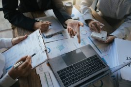 Team of business investment consultant analyzing company annual financial report working with documents pie and donut chart, using laptop, Business and Financial concept.
